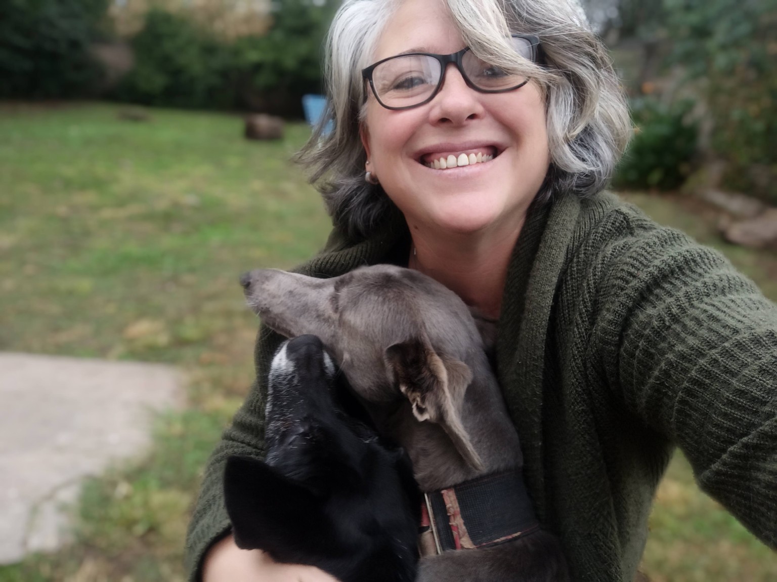 Romi Gallo sonríe en el jardín junto a dos perros.